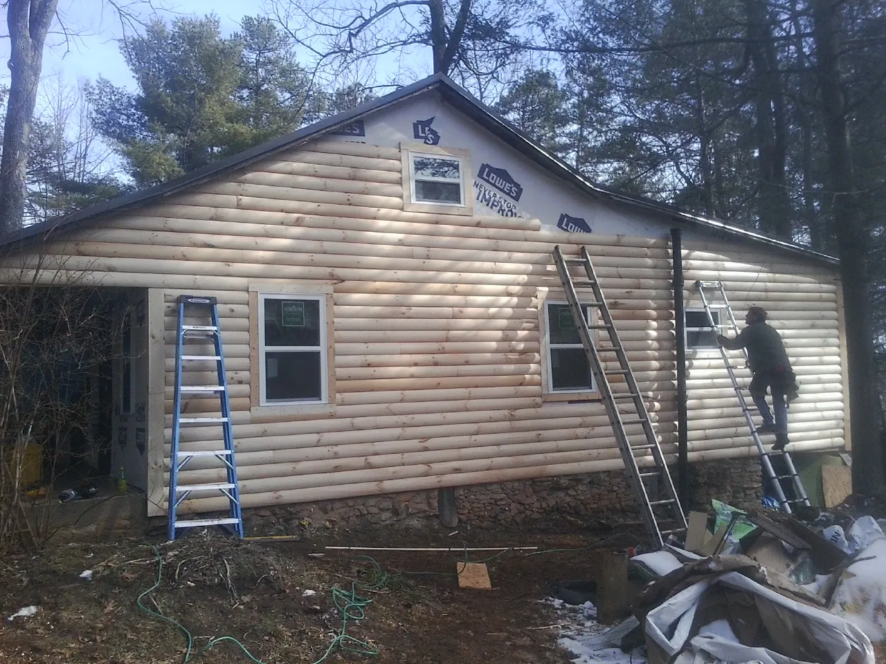 Ladders set against fresh log siding during an exterior remodel in Hills