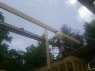 Carpenter setting a ridge beam over a new addition frame — Ice Dam Removal by Roofing Brothers in Hills