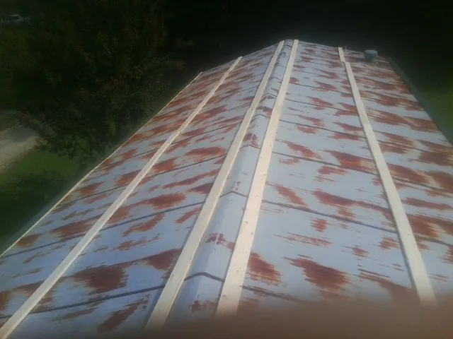 Rusted metal roof panels with new wood purlins before replacement — Storm Damage Roof Repair in Hills by Roofing Brothers