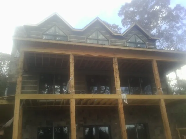 Dormers and porch framing on a large log home under construction — Roof Coating work by our crew in Hills